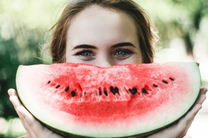 A woman smiling with a smile holding a smily watermelon